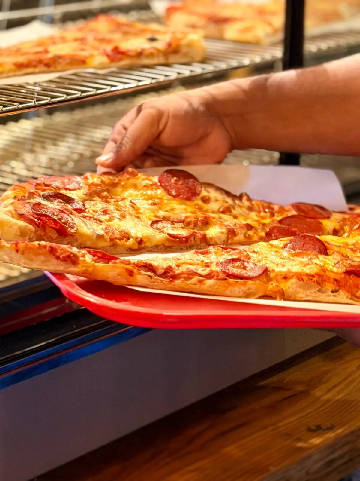 Slices of pepperoni pizza being served on a red tray